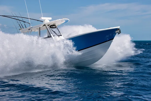 Small motorboat travelling at speed across open water, with spray rising along the bow.