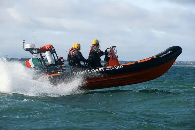 Rigid inflatable boat operating at speed on open water with crew on deck.